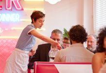 Waitress Pouring Coffee For Customers In 1950s Styled Diner