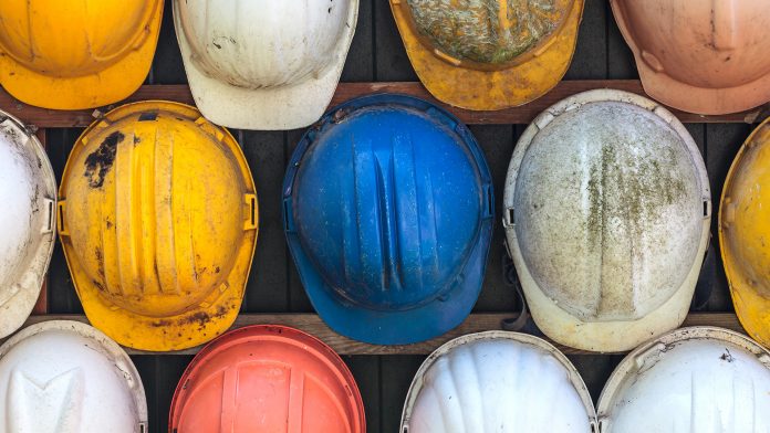 Old and worn construction helmets on wall