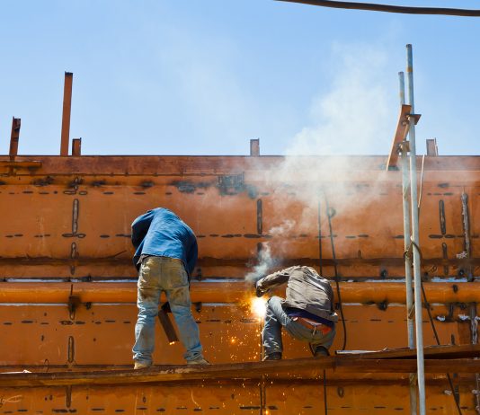 Construction workers welding ship