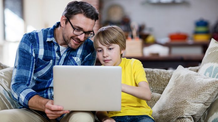 Father helping son on computer