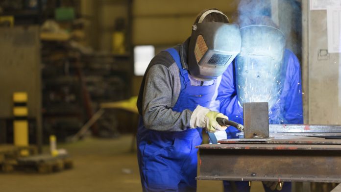 Two steel construction workers welding metal