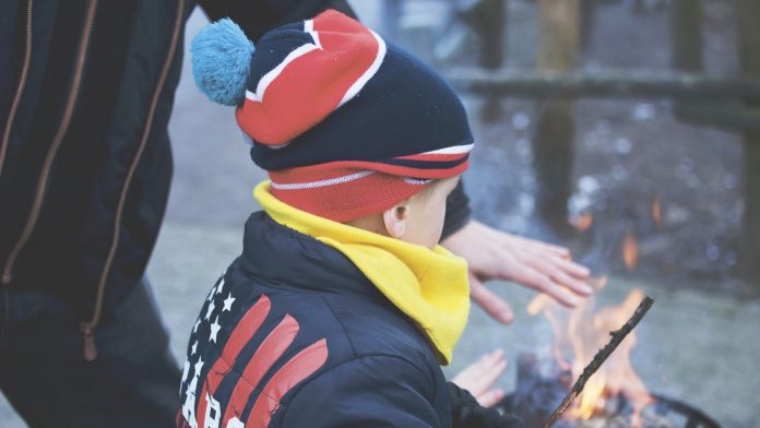 Child outside with campfire