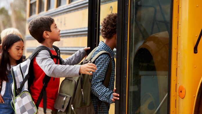 Elementary school kids climbing on to a school bus