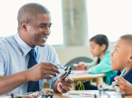 Man is teaching elementary little boy about robotics during school STEM program