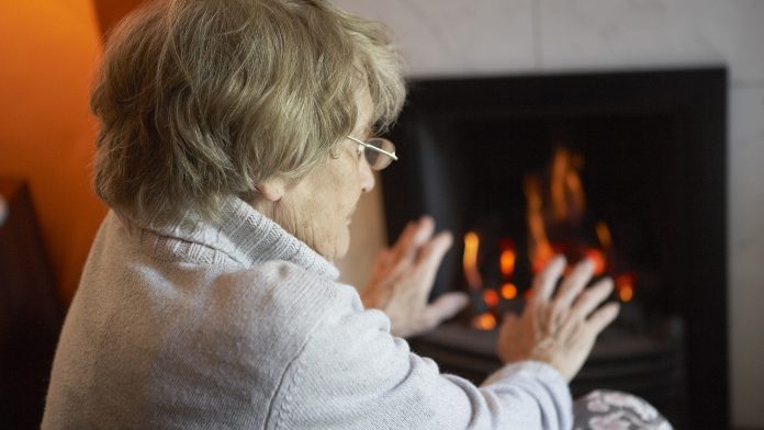 Senior citizen keeping warm by the fire