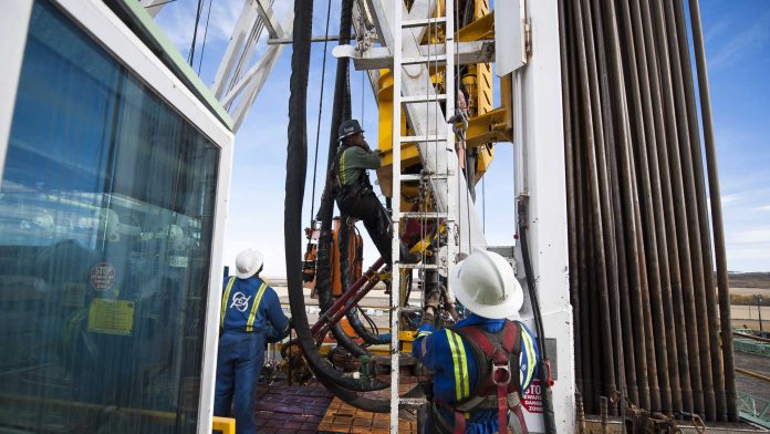 Fracking rig workers climb main drill tower. energy