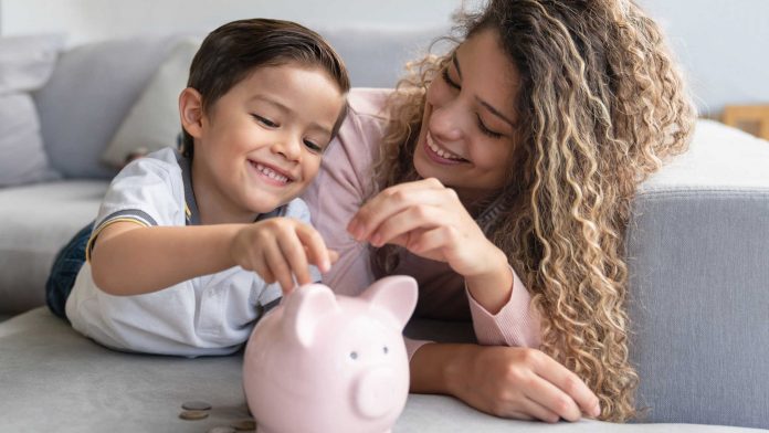 Happy mother and son saving money in a piggybank