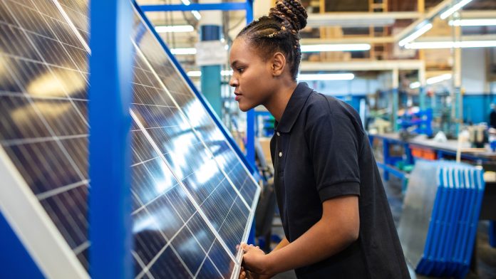 Quality engineer examining solar panels in factory