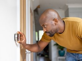 Man adjusting the temperature on the thermostat of his house