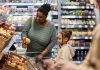 Young woman with little girl shopping for groceries in supermarket