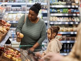 Young woman with little girl shopping for groceries in supermarket