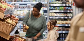 Young woman with little girl shopping for groceries in supermarket