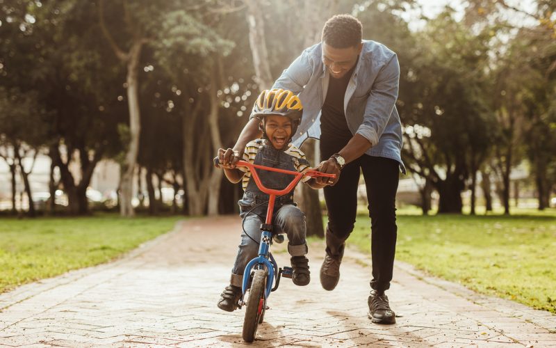 Father teaching his son cycling at park