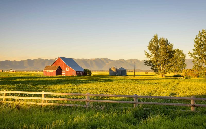 Summer sunset with a red barn in rural Montana and Rocky Mountains