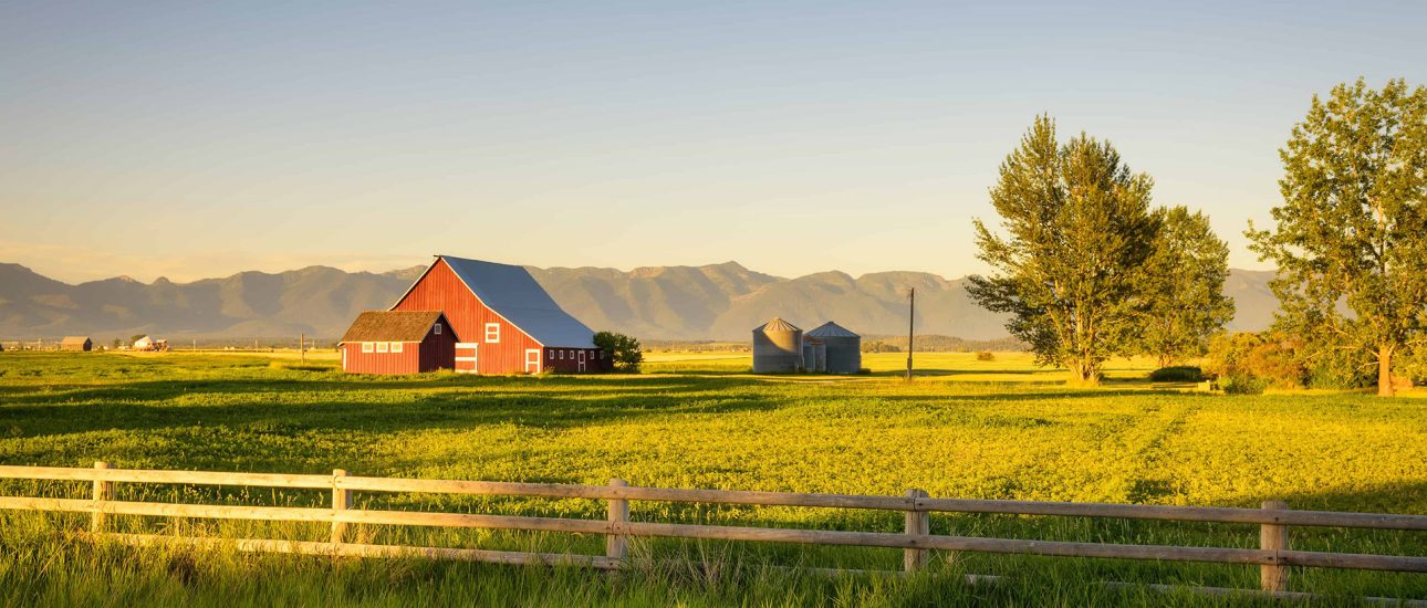 Summer sunset with a red barn in rural Montana and Rocky Mountains