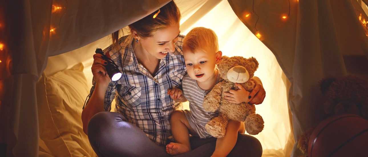 Mother and baby son with a book and a flashlight before going to bed