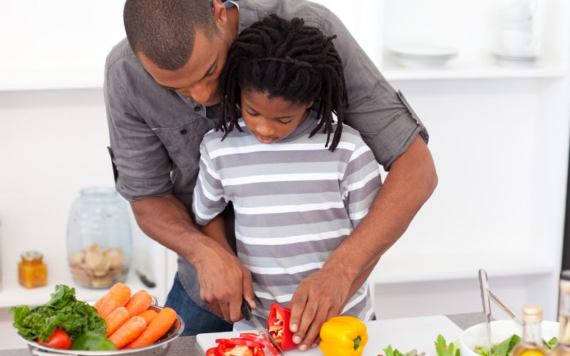 Dad helping son cut vegetables