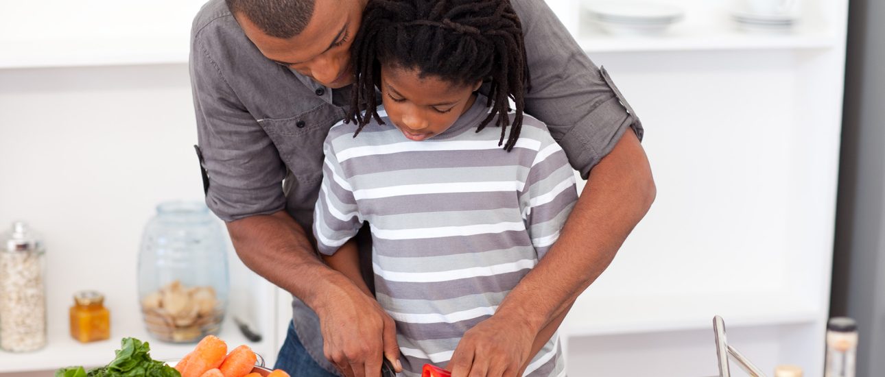 Dad helping son cut vegetables