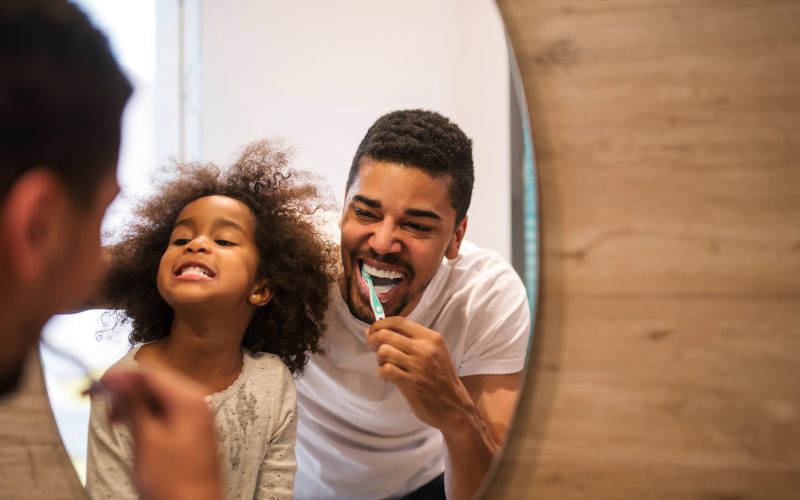 Dad showing daughter how to brush teeth