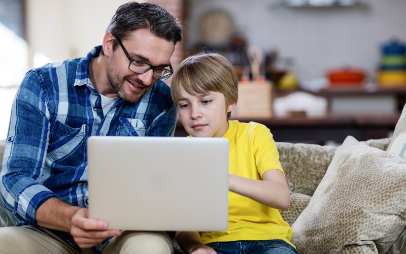 Father helping son on computer