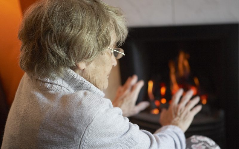 Senior citizen keeping warm by the fire