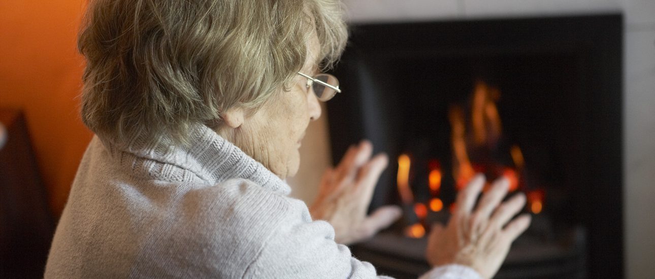 Senior citizen keeping warm by the fire