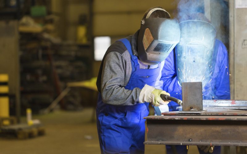 Two steel construction workers welding metal