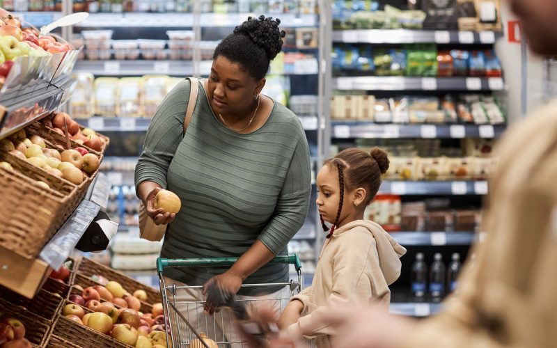 Young woman with little girl shopping for groceries in supermarket