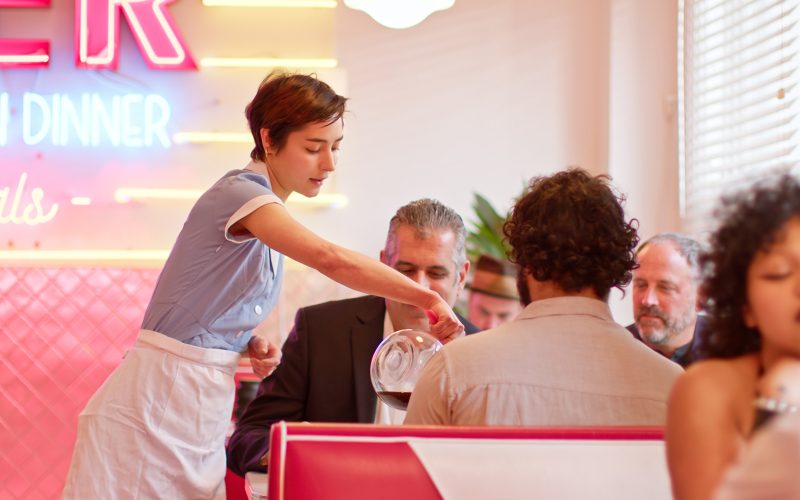 Waitress Pouring Coffee For Customers In 1950s Styled Diner