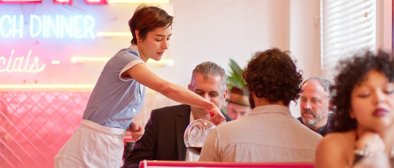 Waitress Pouring Coffee For Customers In 1950s Styled Diner