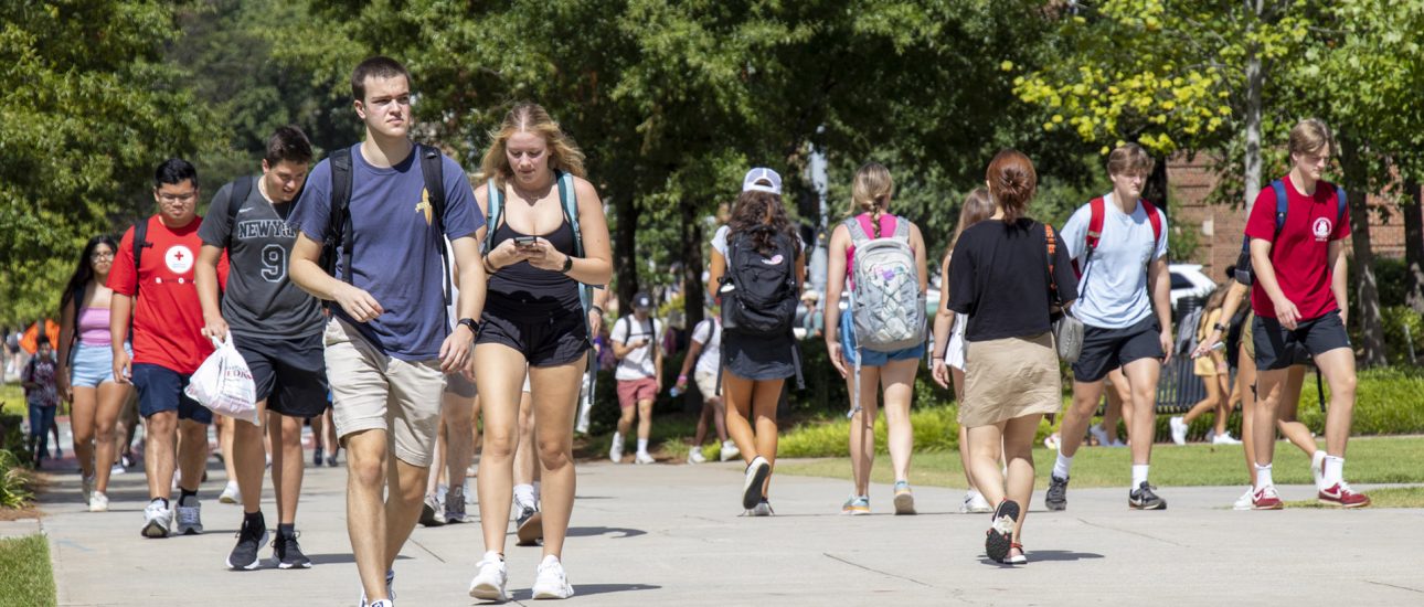 Students walking outside on a bright sunny day on campus