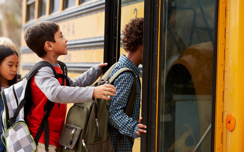 Elementary school kids climbing on to a school bus